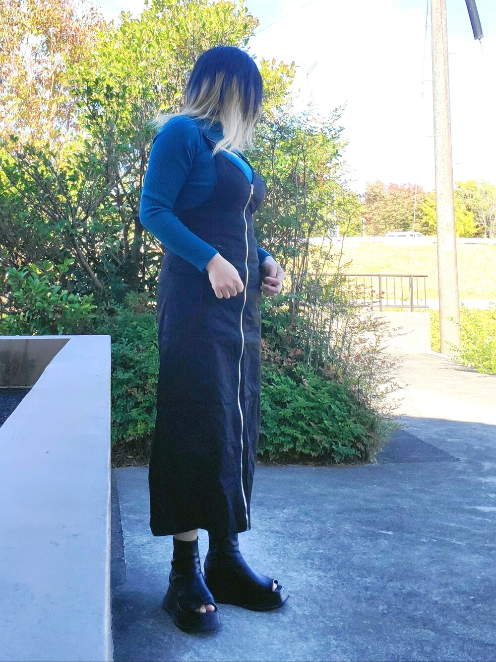 ブラック系のジャンパースカート、ブラック系のサンダル、ブルー系のニット/セーターを着用したレディースの秋コーディネートの3枚目の写真