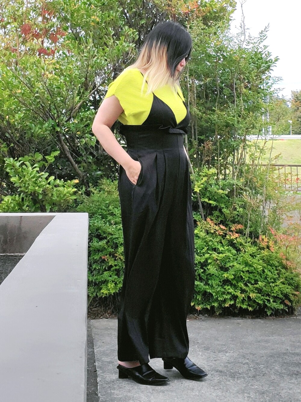 ブラック系のサロペット/オーバーオール、グリーン系のニット/セーター、ブラック系のパンプスを着用したレディースの秋コーディネートの3枚目の写真