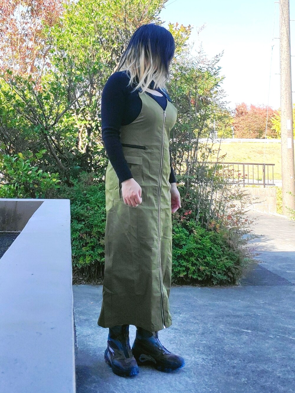 グリーン系のジャンパースカート、ブラック系のスニーカー、ブラック系のニット/セーターを着用したレディースの秋コーディネートの3枚目の写真