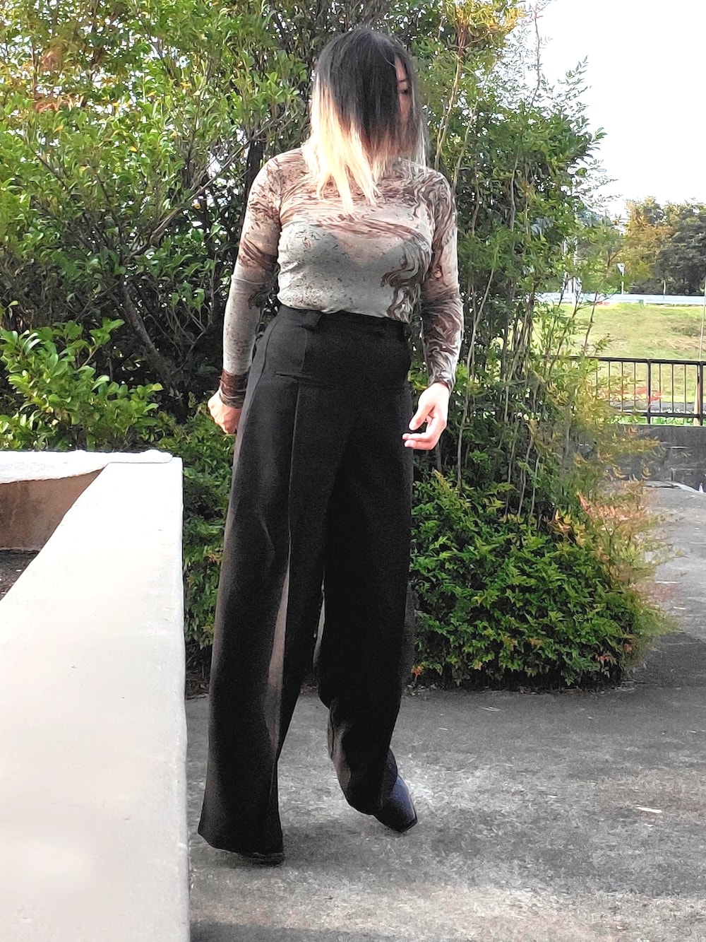 ブラック系のスラックス、グリーン系のTシャツ/カットソー、ブラック系のパンプスを着用したレディースの秋コーディネートの5枚目の写真