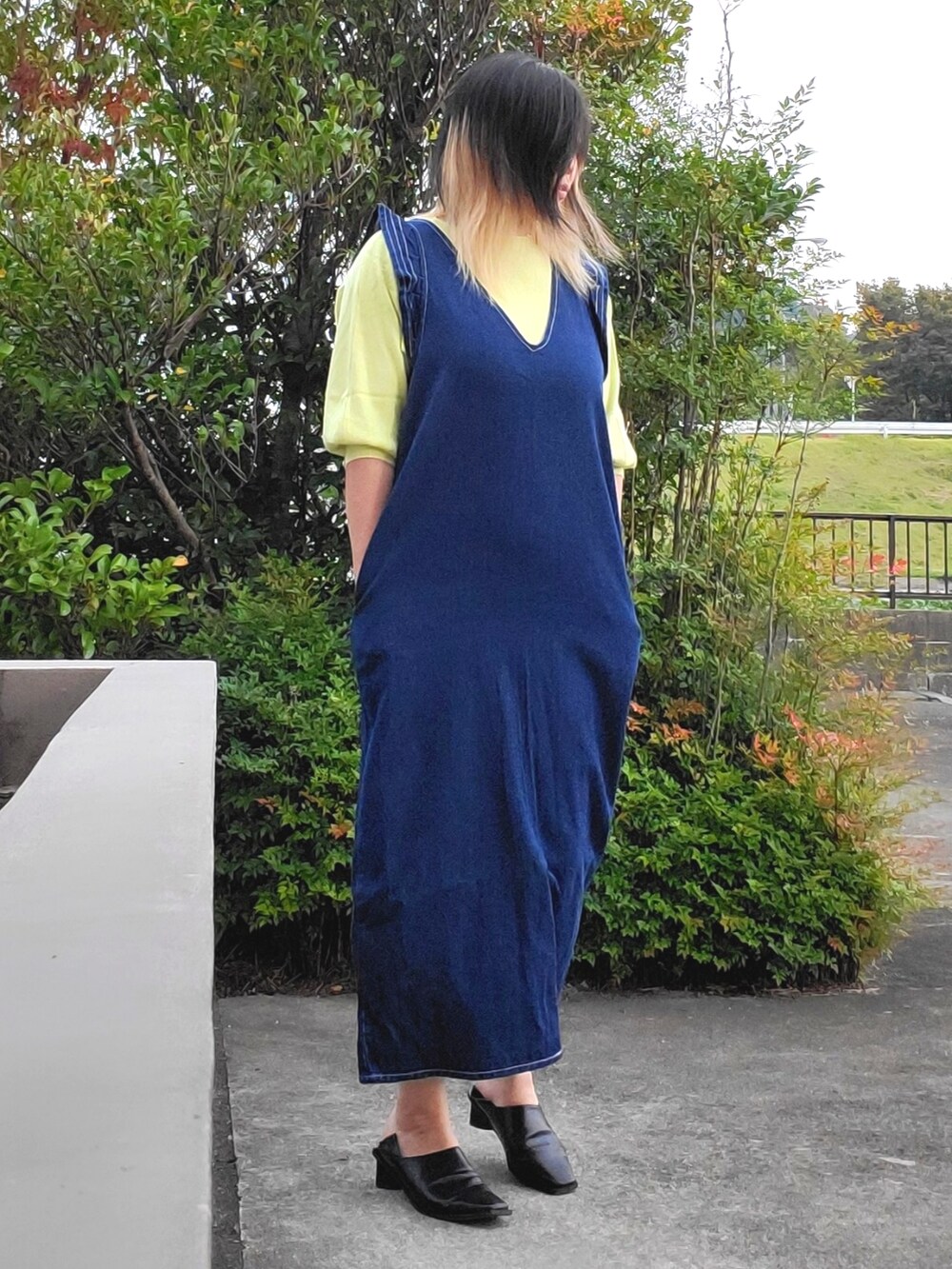 ブラック系のパンプス、ブルー系のワンピース、イエロー系のニット/セーターを着用したレディースの秋コーディネートの2枚目の写真