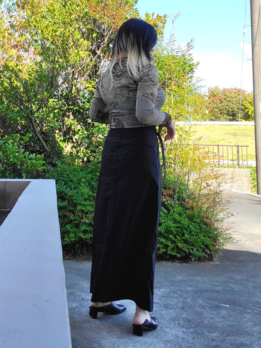 ブラック系のパンプス、ブラック系のスカート、グリーン系のTシャツ/カットソーを着用したレディースの秋コーディネートの3枚目の写真