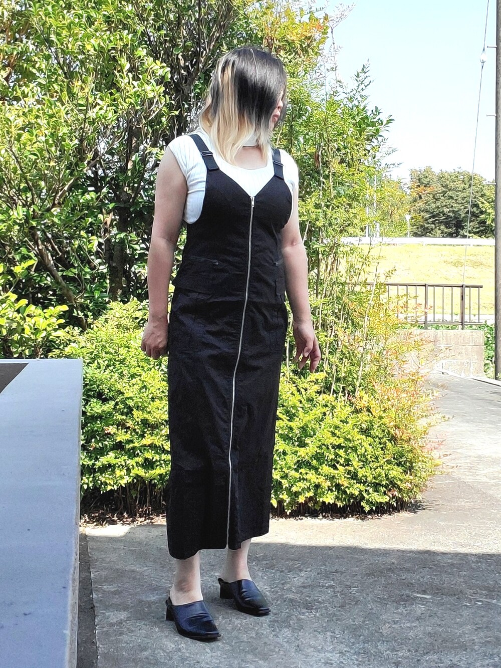 ブラック系のジャンパースカート、ホワイト系のニット/セーター、ブラック系のパンプスを着用したレディースの秋コーディネートの2枚目の写真