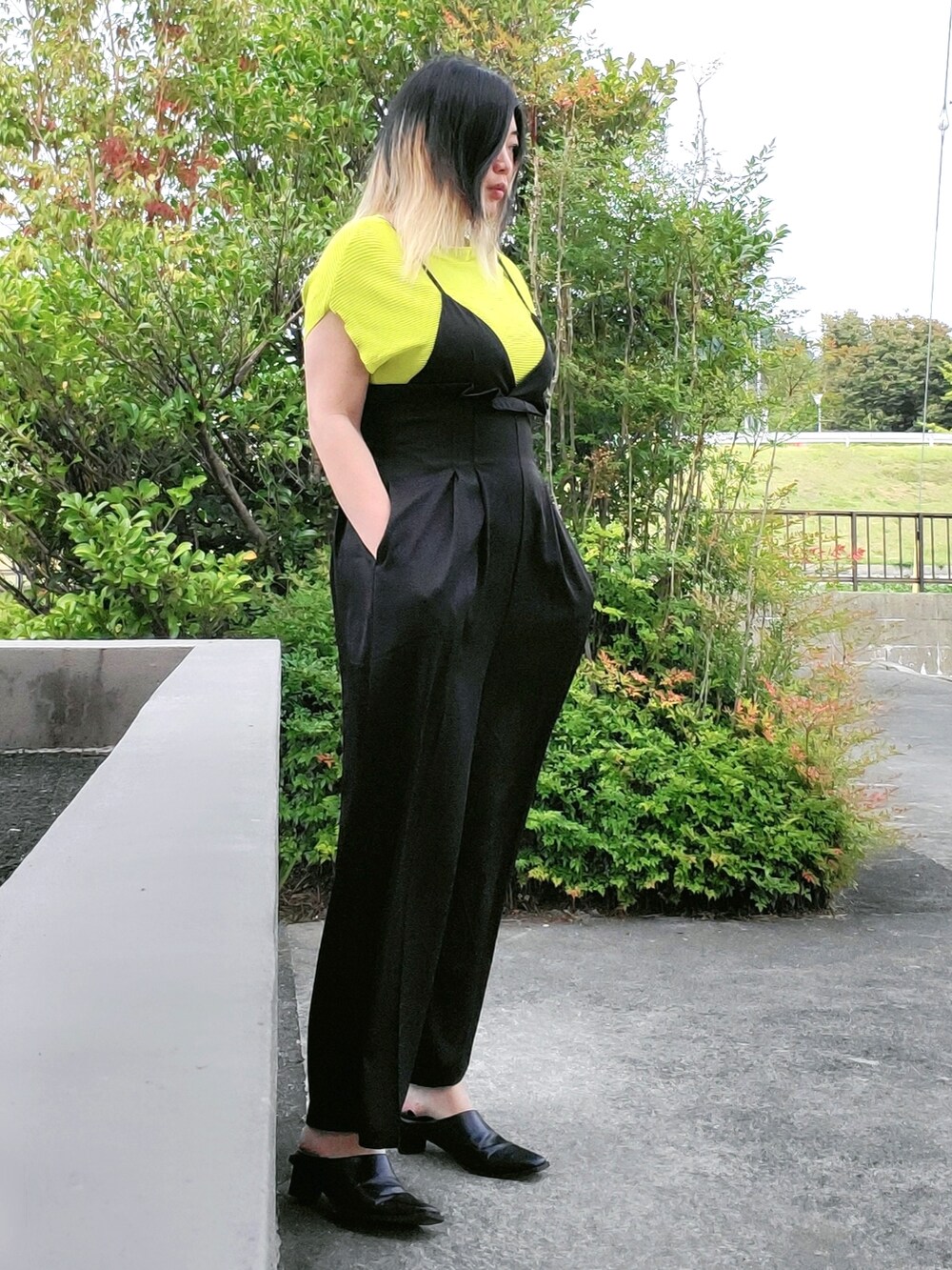 ブラック系のサロペット/オーバーオール、グリーン系のニット/セーター、ブラック系のパンプスを着用したレディースの秋コーディネートの2枚目の写真