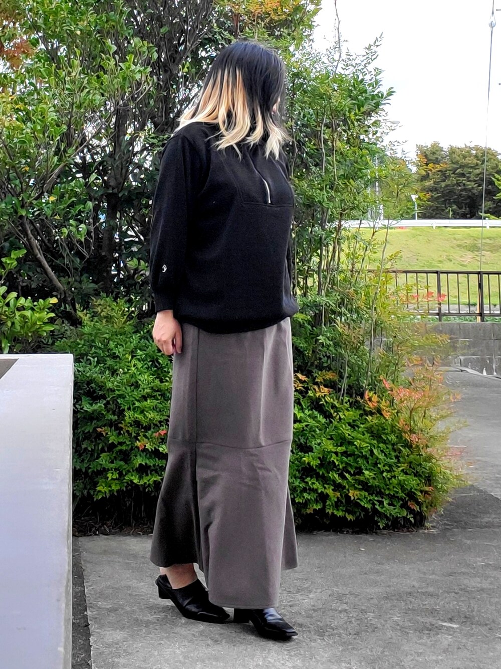 ブラック系のパンプス、グレー系のスカート、ブラック系のニット/セーターを着用したレディースの秋コーディネートの5枚目の写真