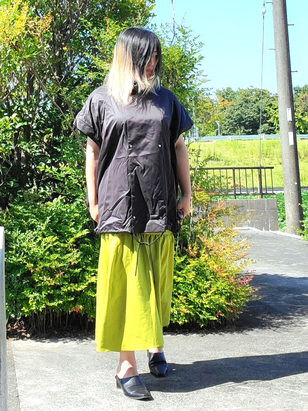 ブラック系のパンプス、グリーン系のスカート、ブラック系のその他アウターを着用したレディースの秋コーディネートの2枚目の写真