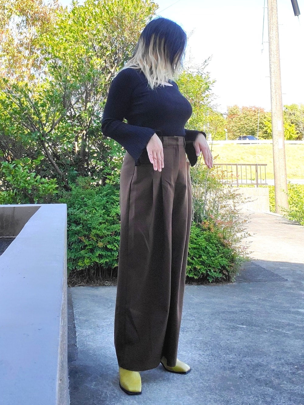 イエロー系のサンダル、ブラウン系のその他パンツ、ブラック系のニット/セーターを着用したレディースの秋コーディネートの2枚目の写真