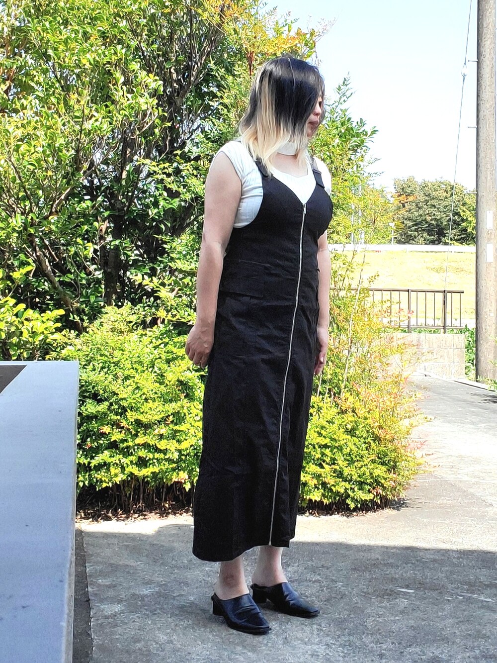 ブラック系のジャンパースカート、ホワイト系のニット/セーター、ブラック系のパンプスを着用したレディースの秋コーディネートの3枚目の写真