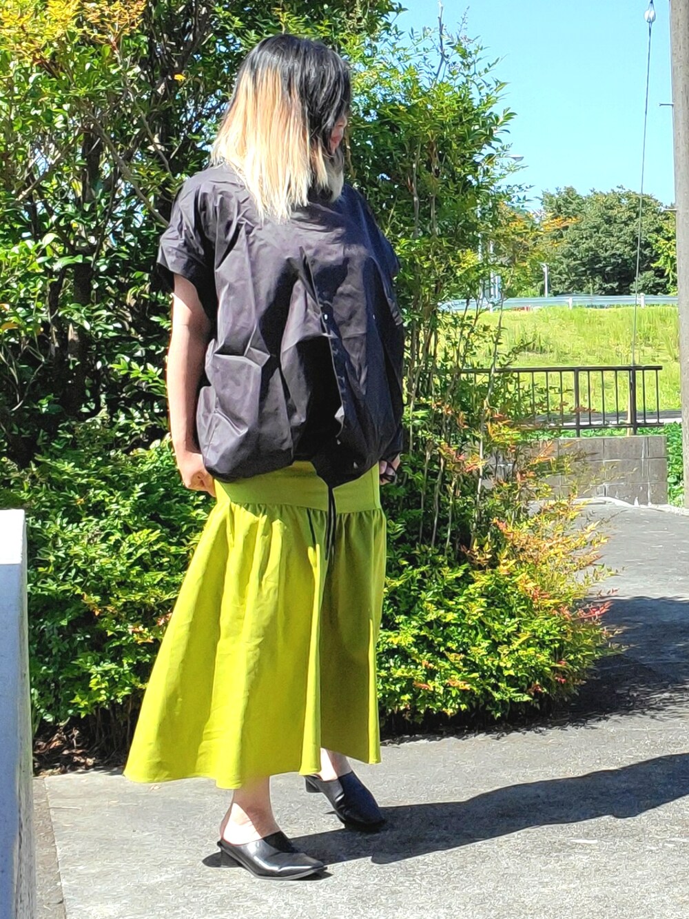 ブラック系のパンプス、グリーン系のスカート、ブラック系のその他アウターを着用したレディースの秋コーディネートの3枚目の写真