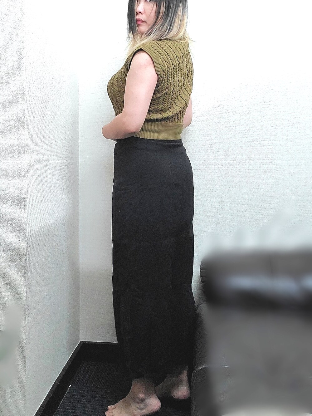 イエロー系のニット/セーター、ブラック系のデニムスカートを着用したレディースの秋コーディネートの4枚目の写真