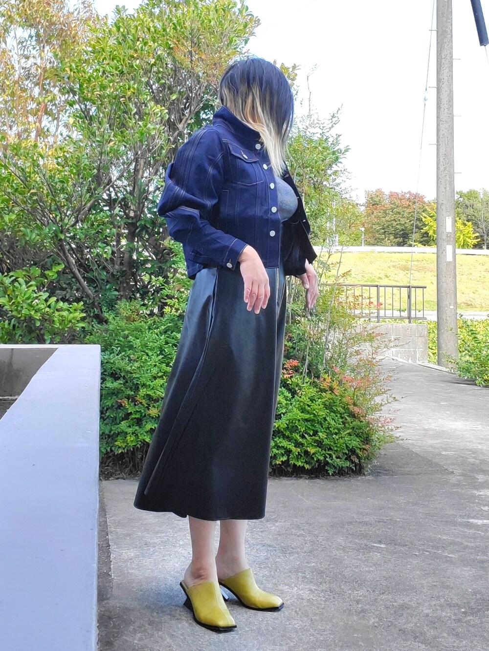 イエロー系のサンダル、ブラック系のワンピース、ブルー系のデニムジャケットを着用したレディースの秋コーディネートの5枚目の写真