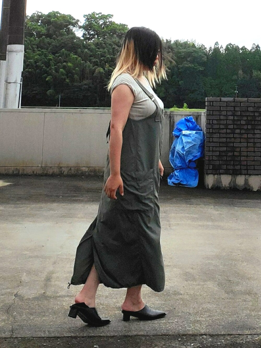 グリーン系のジャンパースカート、ベージュ系のニット/セーター、ブラック系のパンプスを着用したレディースの秋コーディネートの2枚目の写真