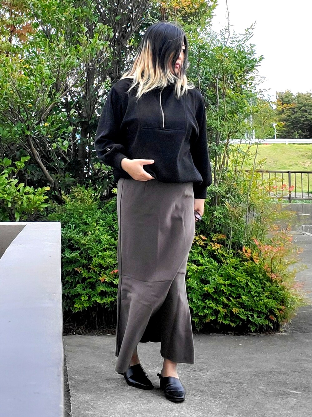 ブラック系のパンプス、グレー系のスカート、ブラック系のニット/セーターを着用したレディースの秋コーディネートの4枚目の写真