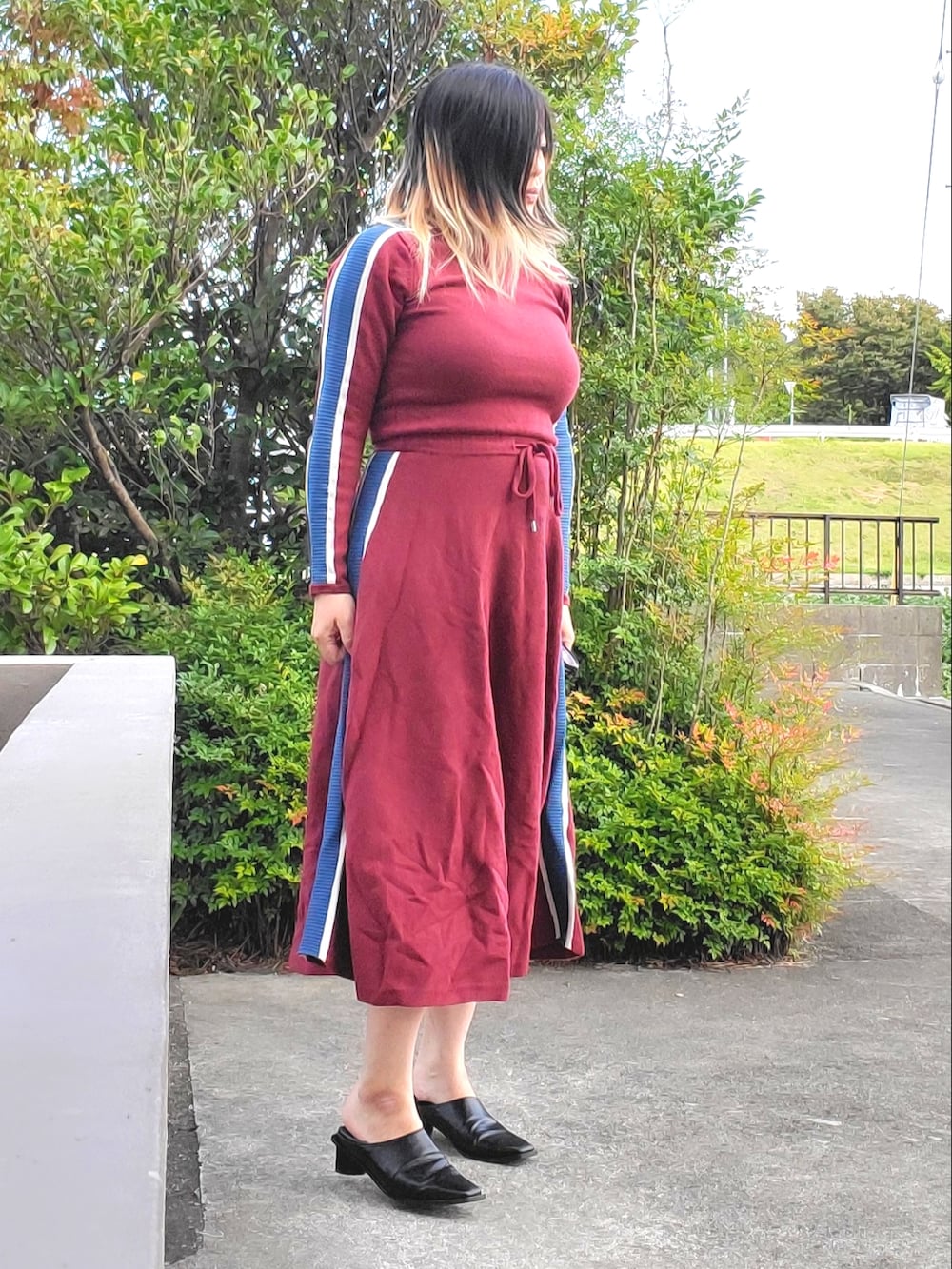 レッド系のワンピース、ブラック系のパンプスを着用したレディースの秋コーディネートの3枚目の写真