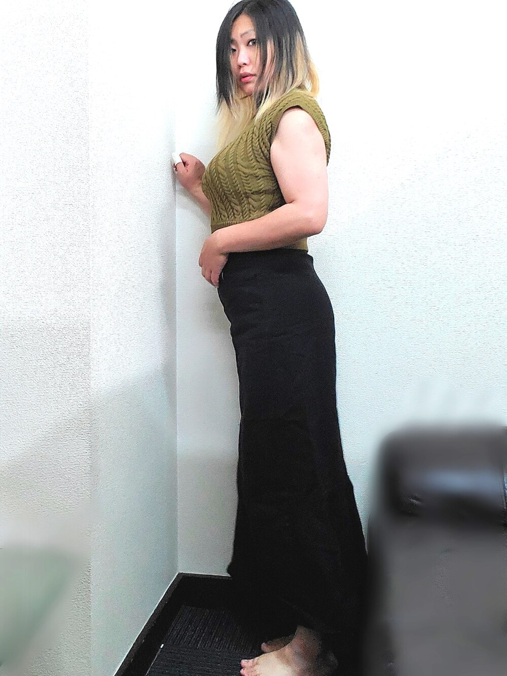 イエロー系のニット/セーター、ブラック系のデニムスカートを着用したレディースの秋コーディネートの2枚目の写真