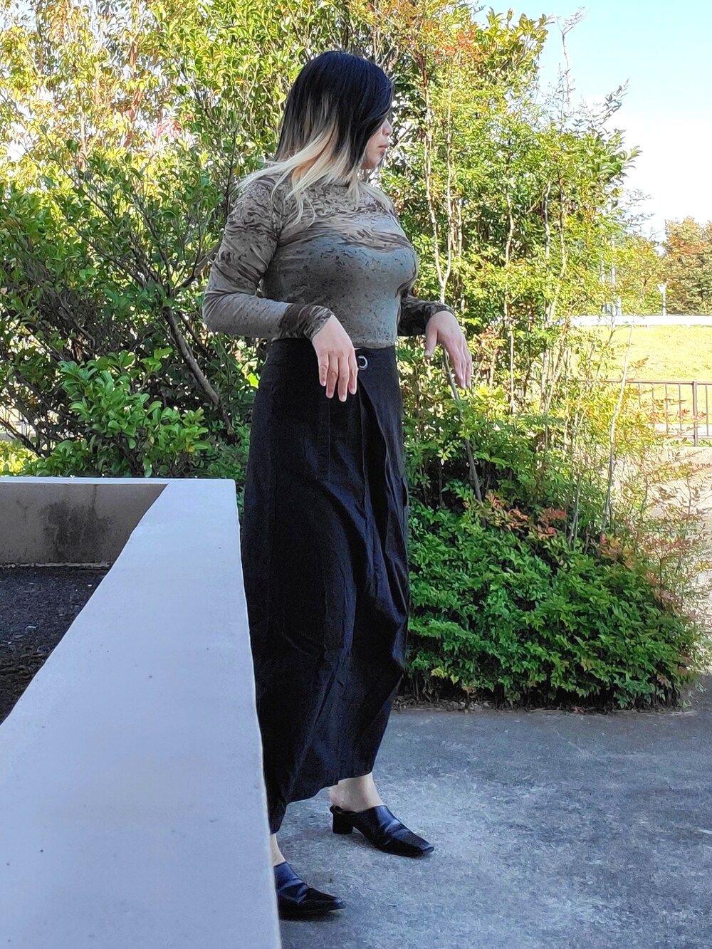 ブラック系のパンプス、ブラック系のスカート、グリーン系のTシャツ/カットソーを着用したレディースの秋コーディネートの5枚目の写真