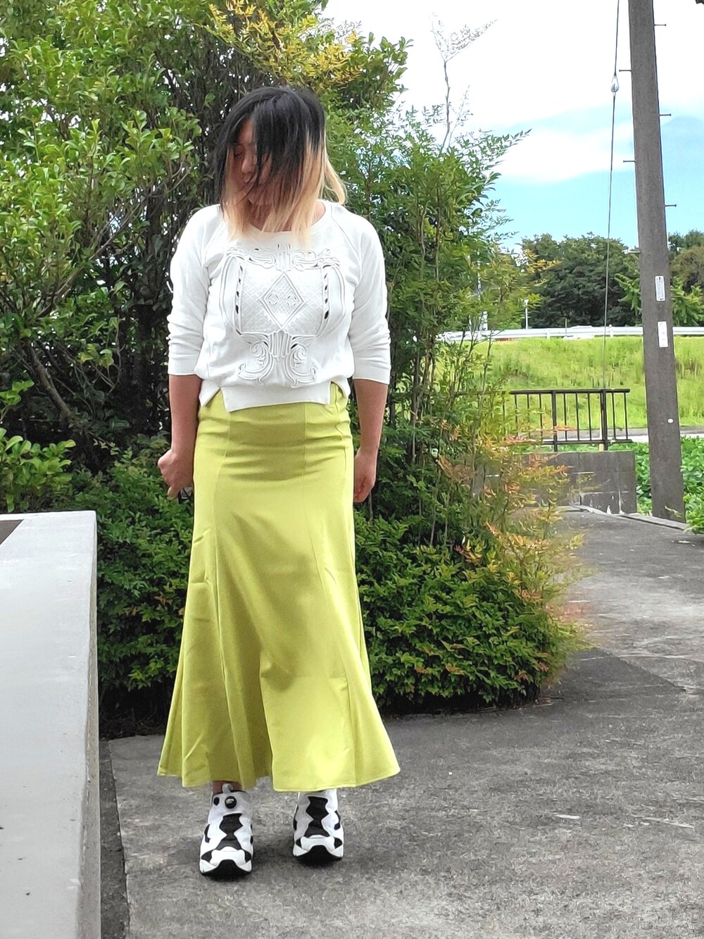 イエロー系のスカート、ホワイト系のTシャツ/カットソー、ホワイト系のスニーカーを着用したレディースの秋コーディネートの2枚目の写真