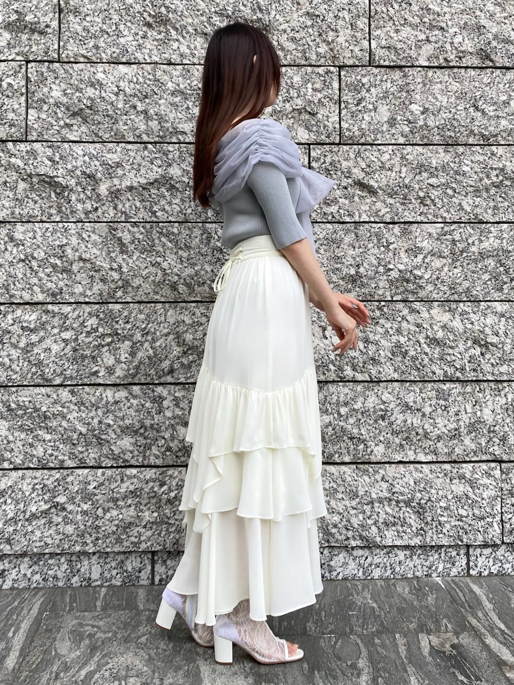 ブルー系のニット/セーター、ホワイト系のスカート、ホワイト系のブーツを着用したレディースの春コーディネートの2枚目の写真