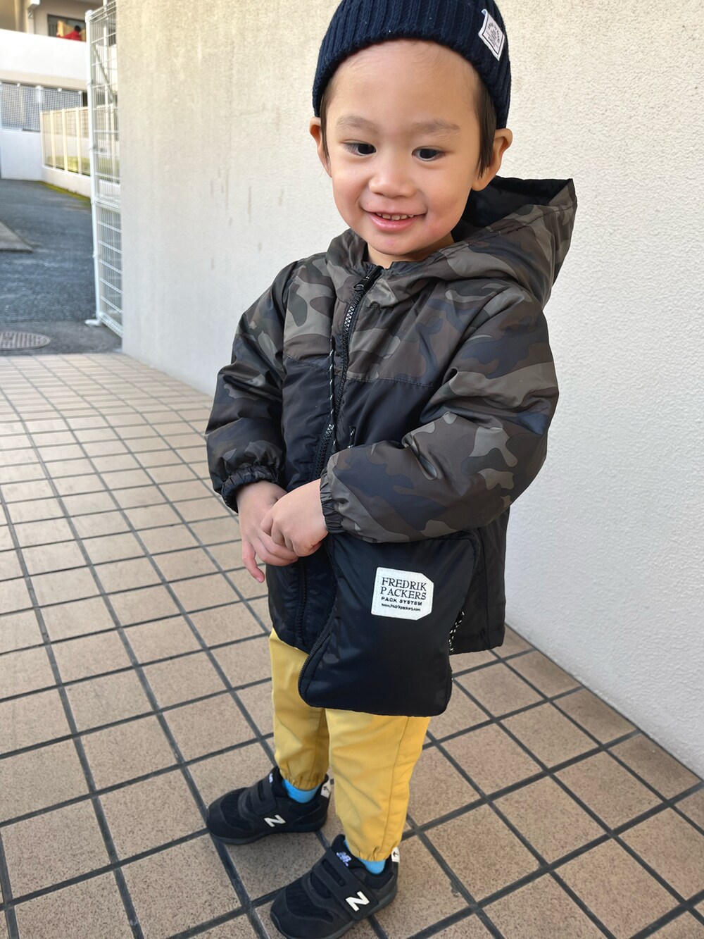 イエロー系のパンツ、ブラック系のブルゾンを着用したキッズの冬コーディネートの2枚目の写真