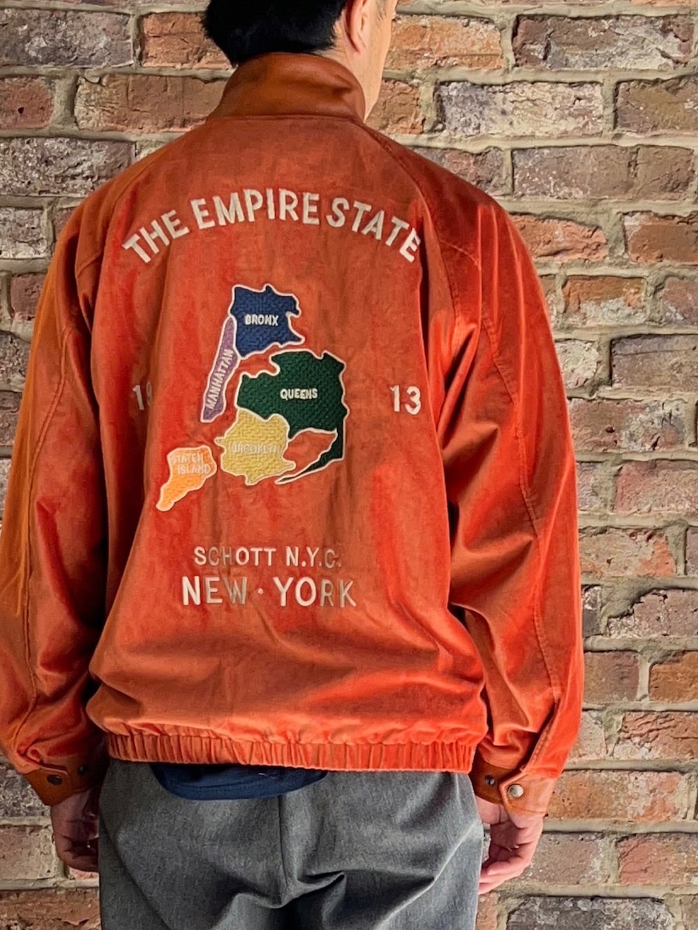 グレー系のパンツ、オレンジ系のブルゾンを着用したメンズの秋コーディネートの3枚目の写真