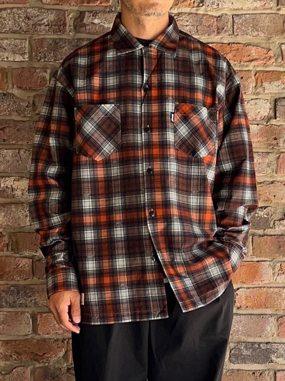 ブラック系のチノパンツ、オレンジ系のシャツ/ブラウスを着用したメンズの夏コーディネートの2枚目の写真