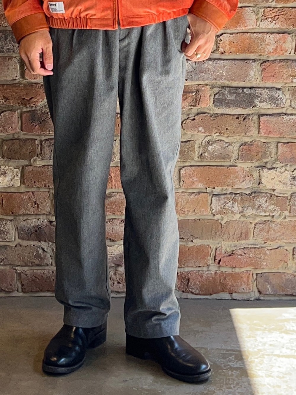 グレー系のパンツ、オレンジ系のブルゾンを着用したメンズの秋コーディネートの4枚目の写真