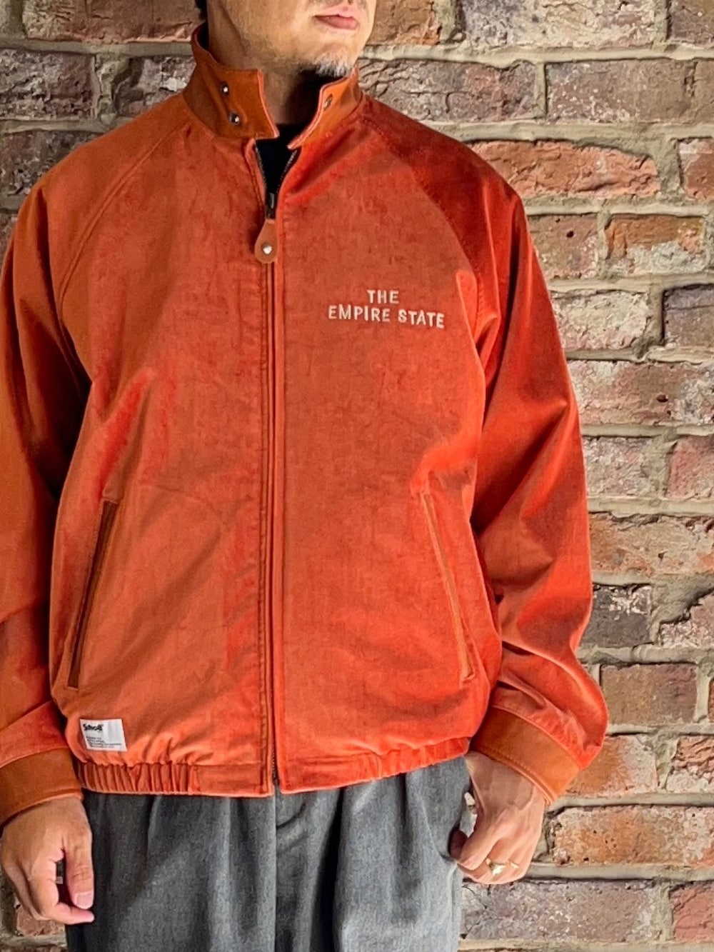 グレー系のパンツ、オレンジ系のブルゾンを着用したメンズの秋コーディネートの2枚目の写真