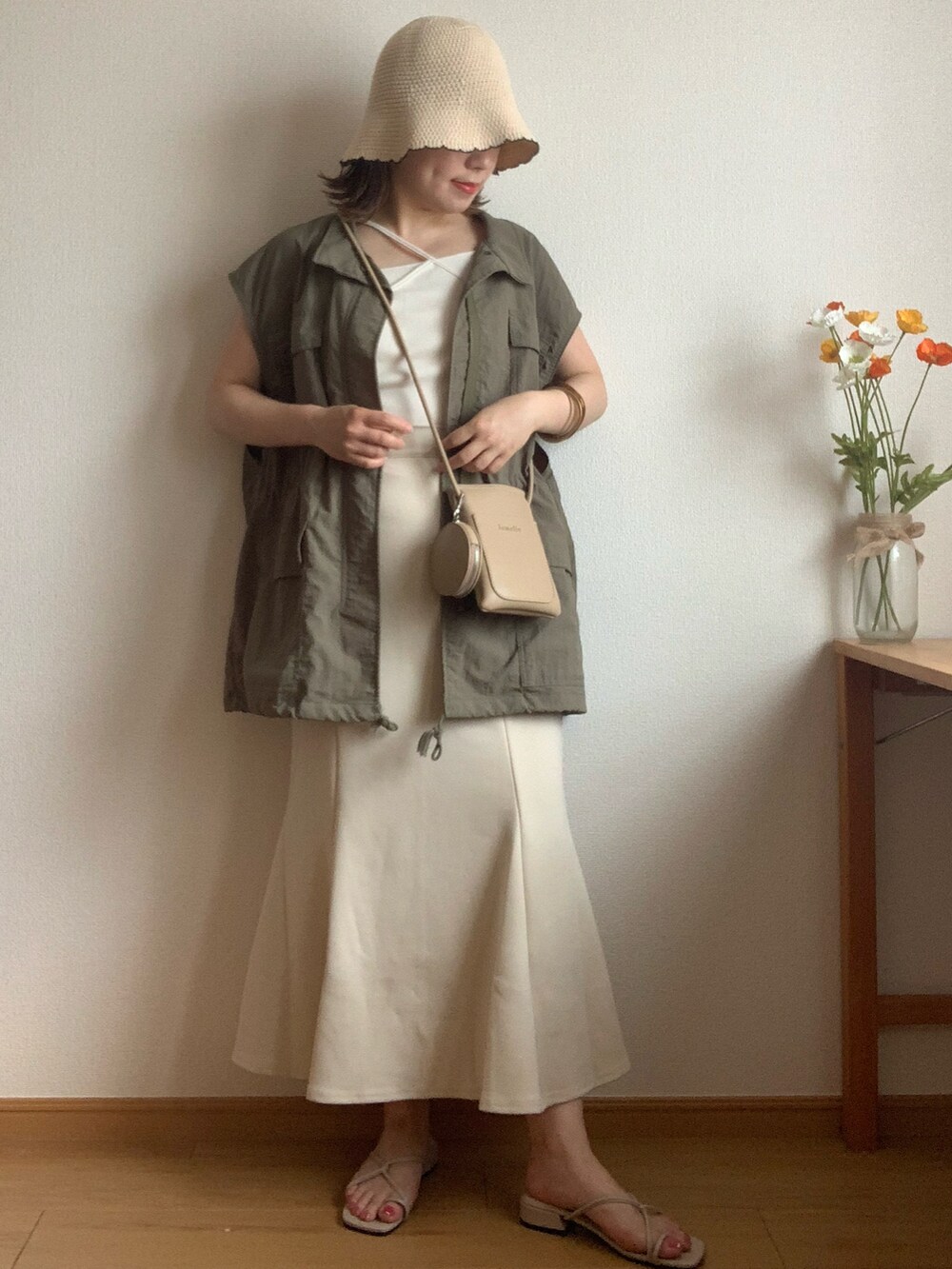 ブラック系のショルダーバッグ、ベージュ系のサンダル、ホワイト系のスカートを着用したレディースの夏コーディネートの2枚目の写真