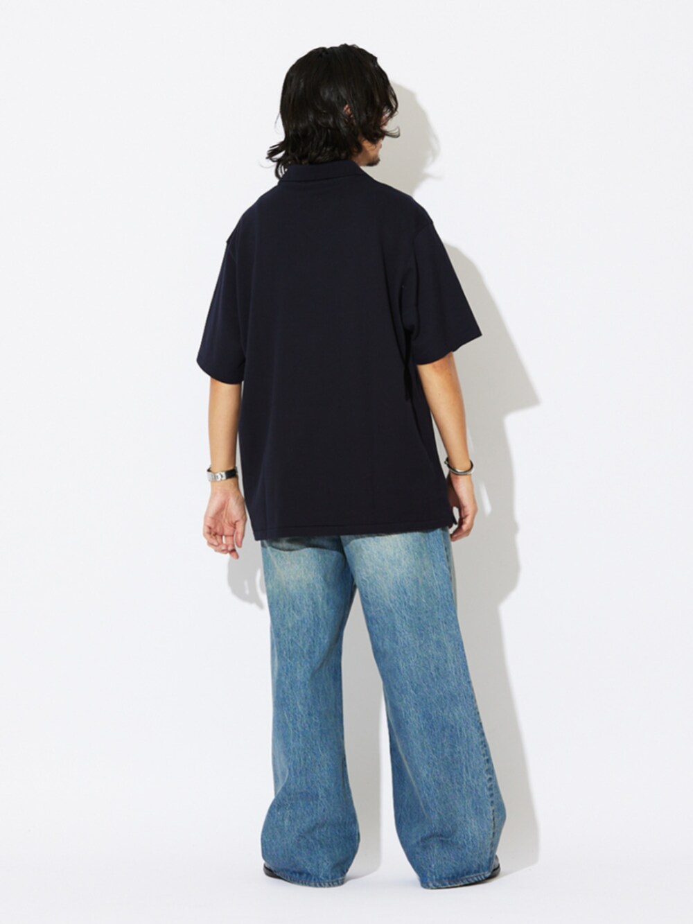 ブラック系のローファー、ブルー系のポロシャツ、ブルー系のデニムパンツを着用したメンズの夏コーディネートの3枚目の写真