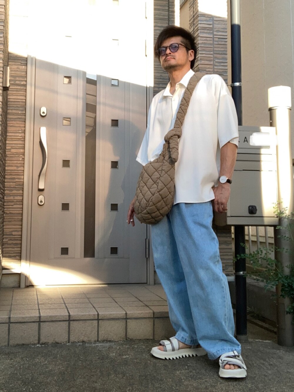 ブルー系のデニムパンツ、ホワイト系のサンダル、ホワイト系のシャツ/ブラウスを着用したメンズの夏コーディネートの2枚目の写真