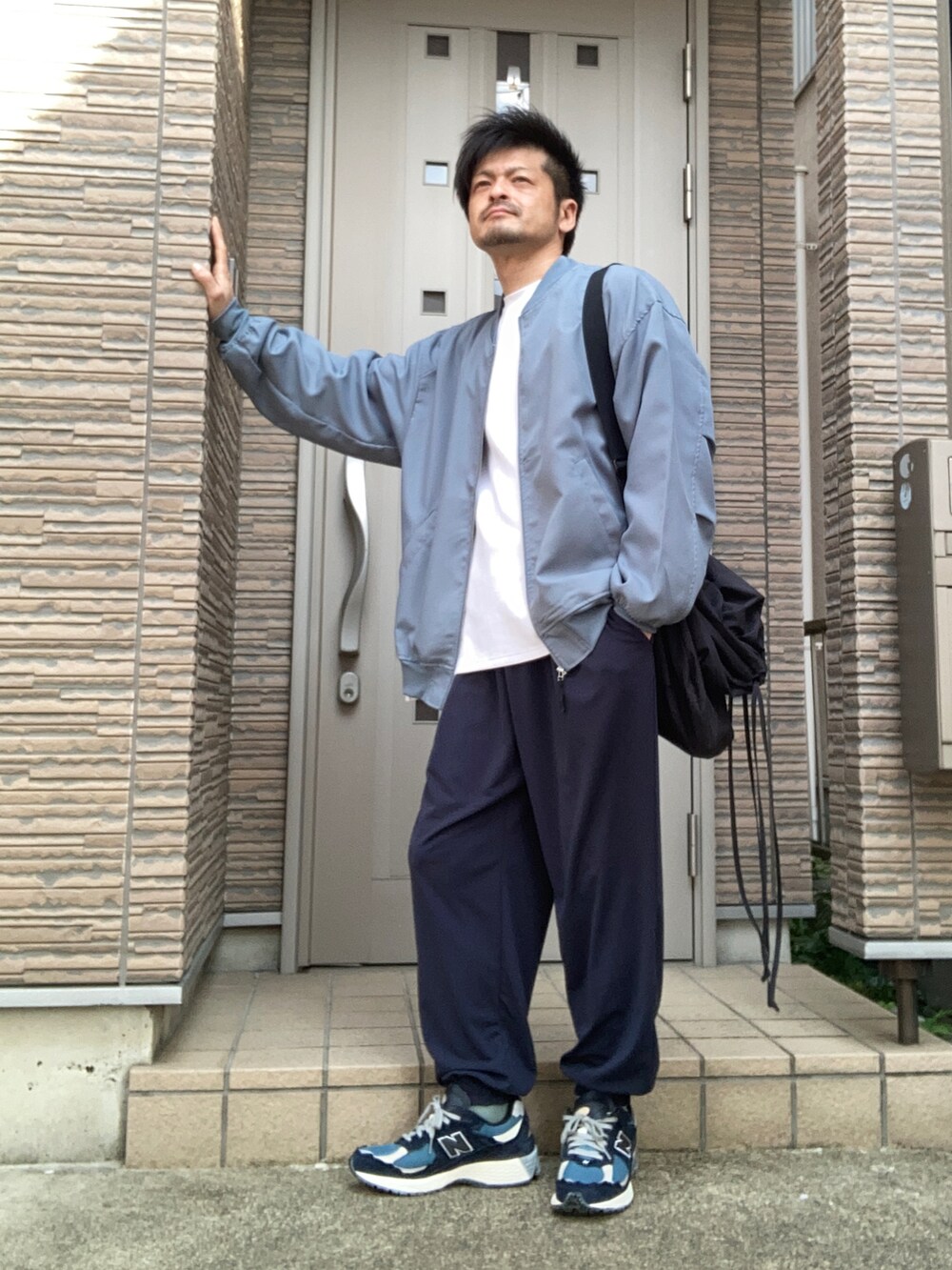 ブルー系のパンツ、ブルー系のスニーカー、ブラック系のショルダーバッグを着用したメンズの春コーディネートの2枚目の写真