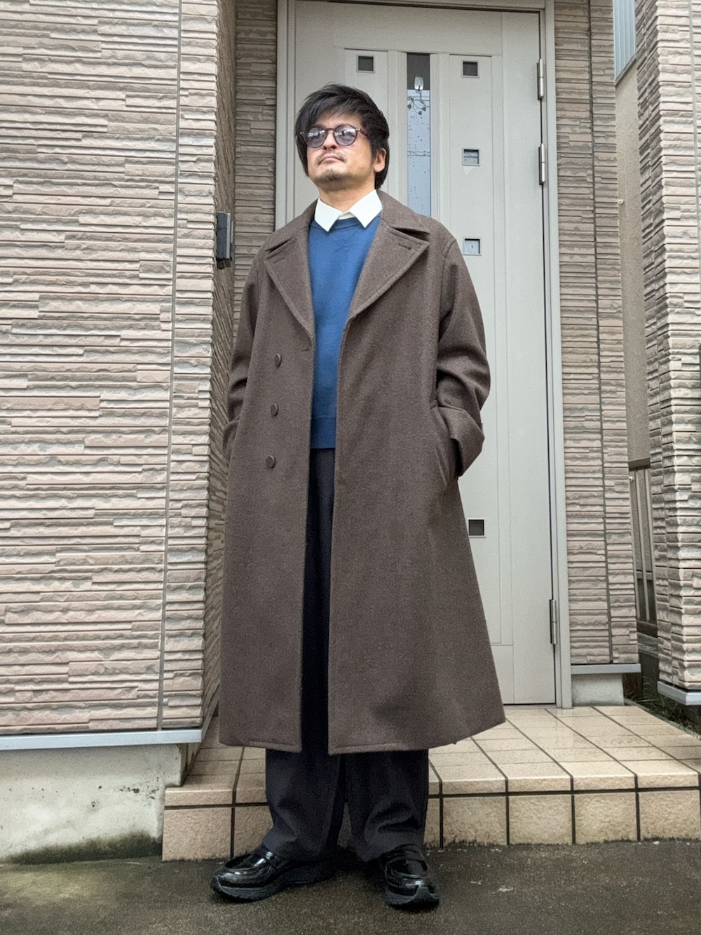 ブラウン系のチェスターコート、グレー系のその他パンツ、ブラック系のスニーカーを着用したメンズの冬コーディネートの3枚目の写真