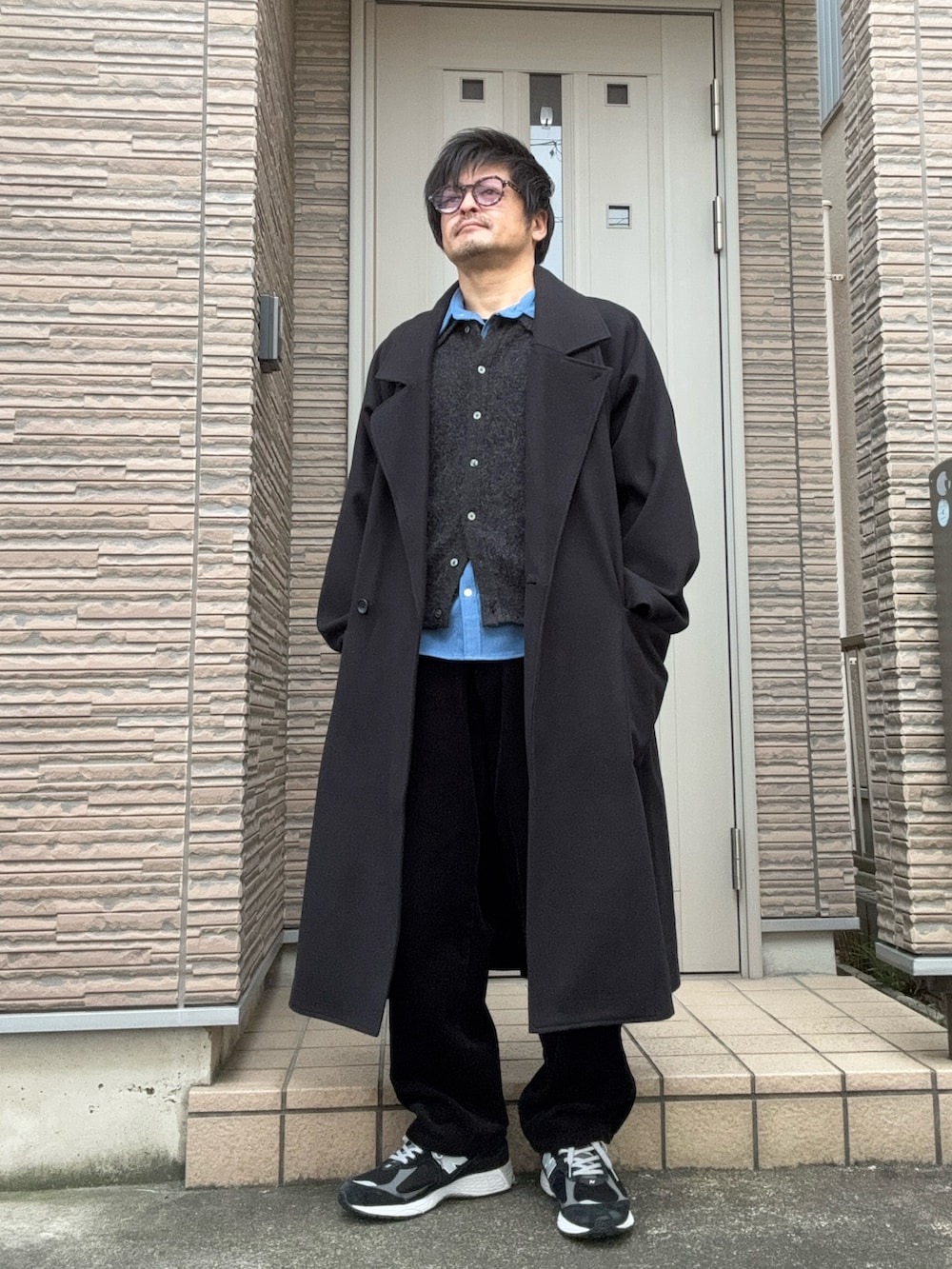 ブラック系のチェスターコート、グレー系のショルダーバッグ、ブラック系のスニーカーを着用したメンズの冬コーディネートの2枚目の写真