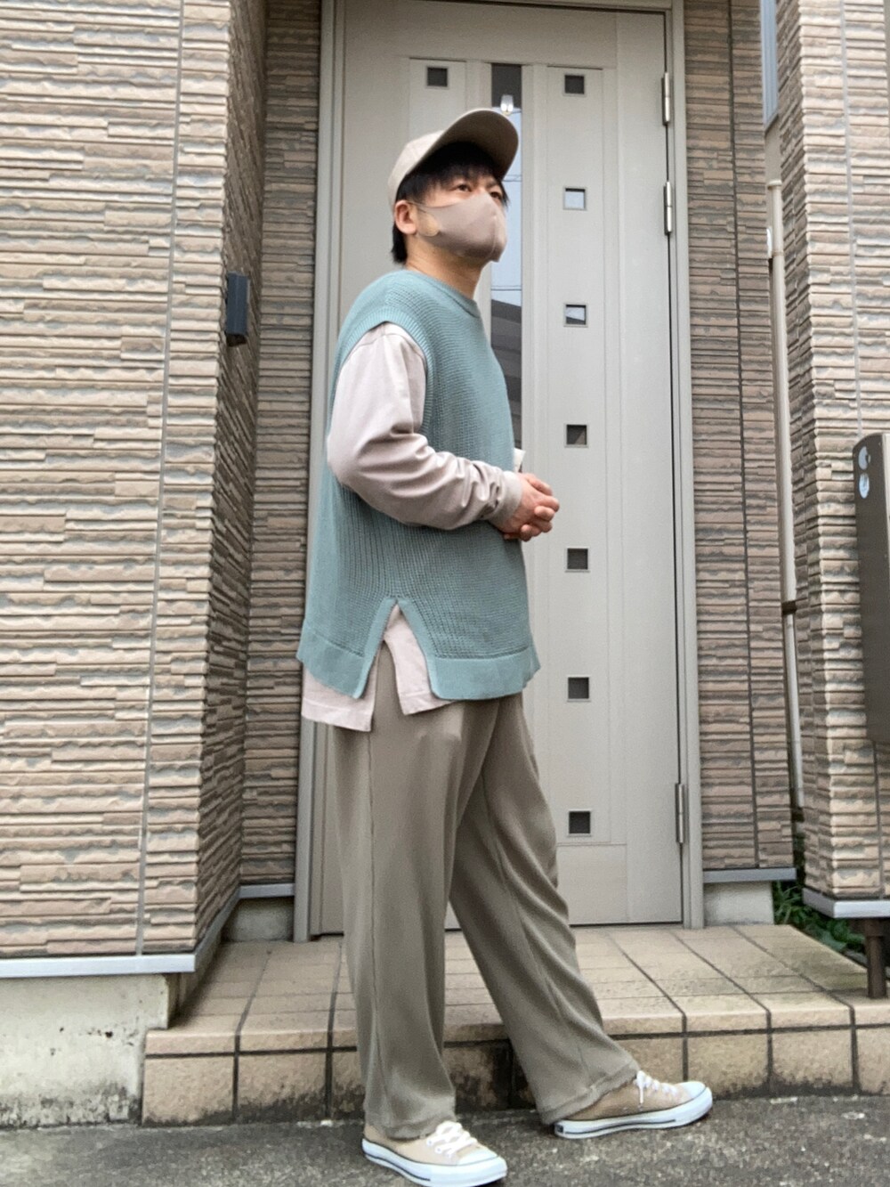 グリーン系のパンツ、ホワイト系のトートバッグ、グリーン系のベストを着用したメンズの春コーディネートの2枚目の写真