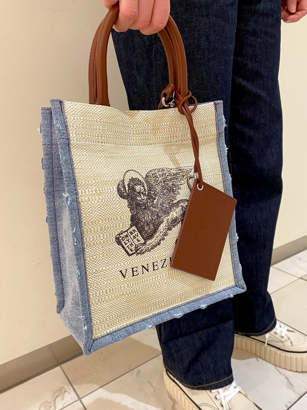 ベージュ系のニット/セーター、ホワイト系のスニーカー、ホワイト系のトートバッグを着用したレディースの春コーディネートの2枚目の写真