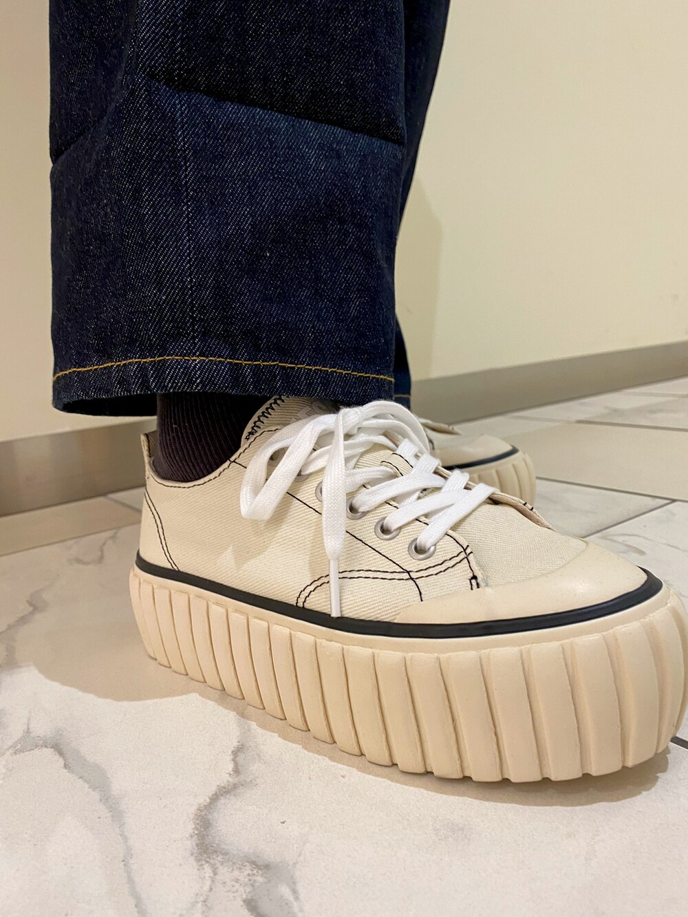 ベージュ系のニット/セーター、ホワイト系のスニーカー、ホワイト系のトートバッグを着用したレディースの春コーディネートの3枚目の写真