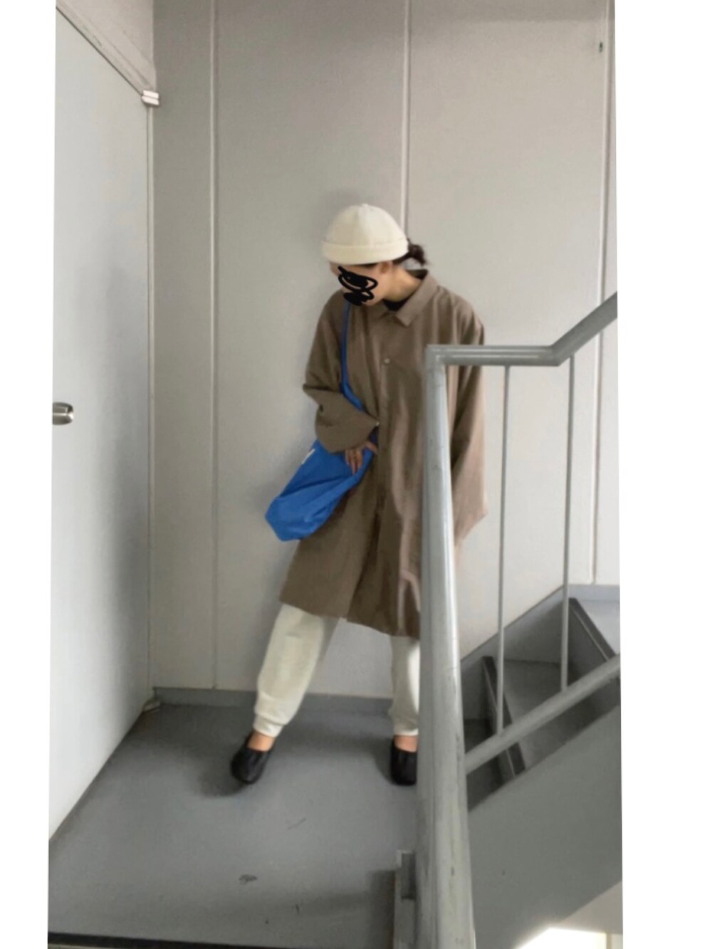 ブラウン系のステンカラーコート、ホワイト系のパンツ、ブルー系のトートバッグを着用したレディースの秋コーディネートの5枚目の写真