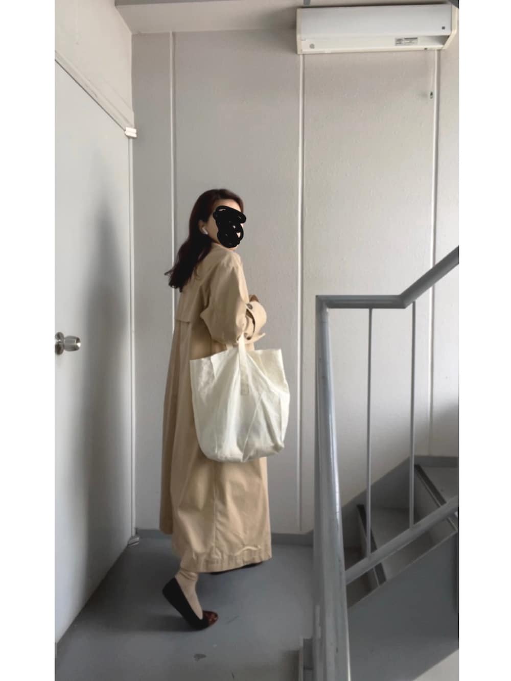 ホワイト系のトートバッグ、ホワイト系のニット/セーター、ベージュ系のトレンチコートを着用したレディースの冬コーディネートの3枚目の写真