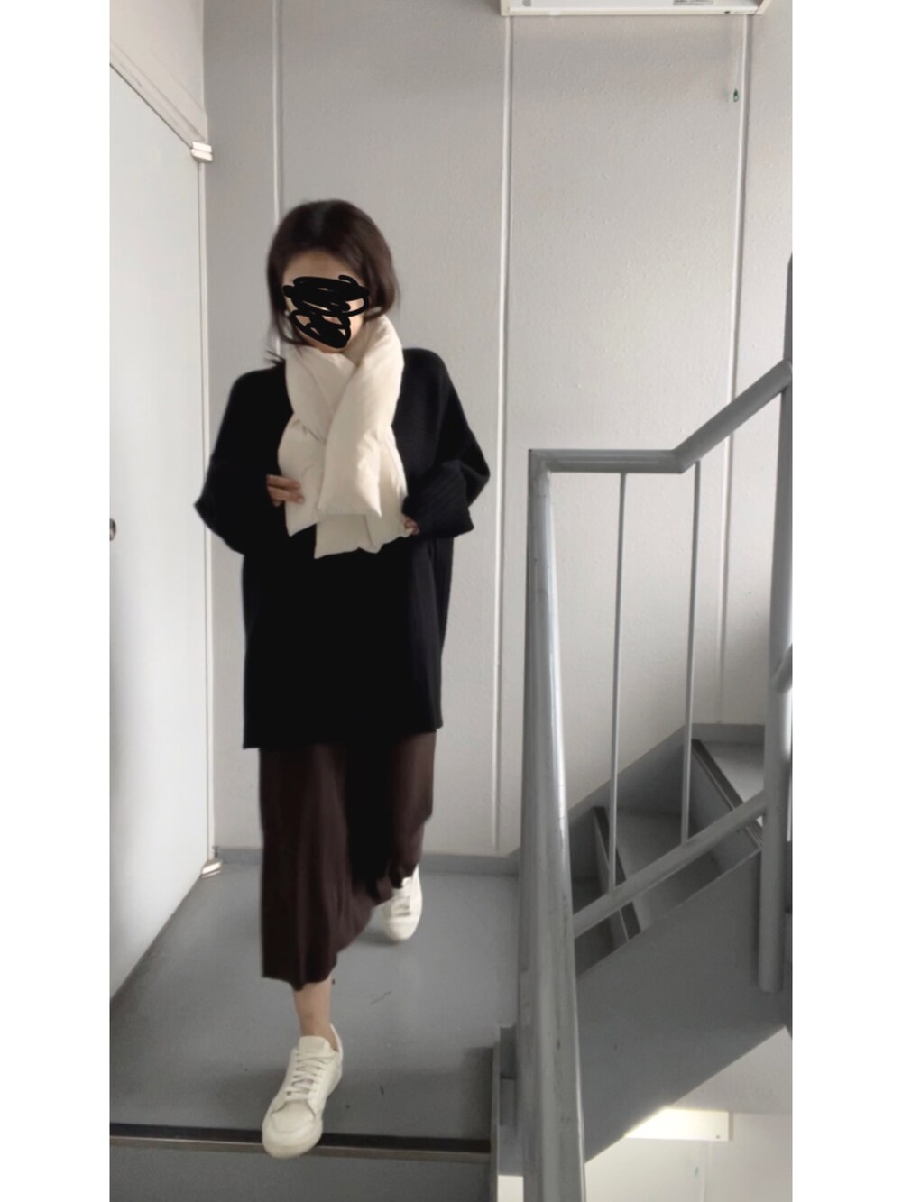 ブラック系のニット/セーター、ブラウン系のスカート、ホワイト系のスニーカーを着用したレディースの冬コーディネートの2枚目の写真