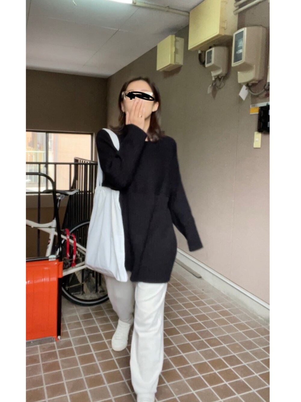 ブラック系のニット/セーター、ホワイト系のパンツ、ホワイト系のスニーカーを着用したレディースの冬コーディネートの3枚目の写真