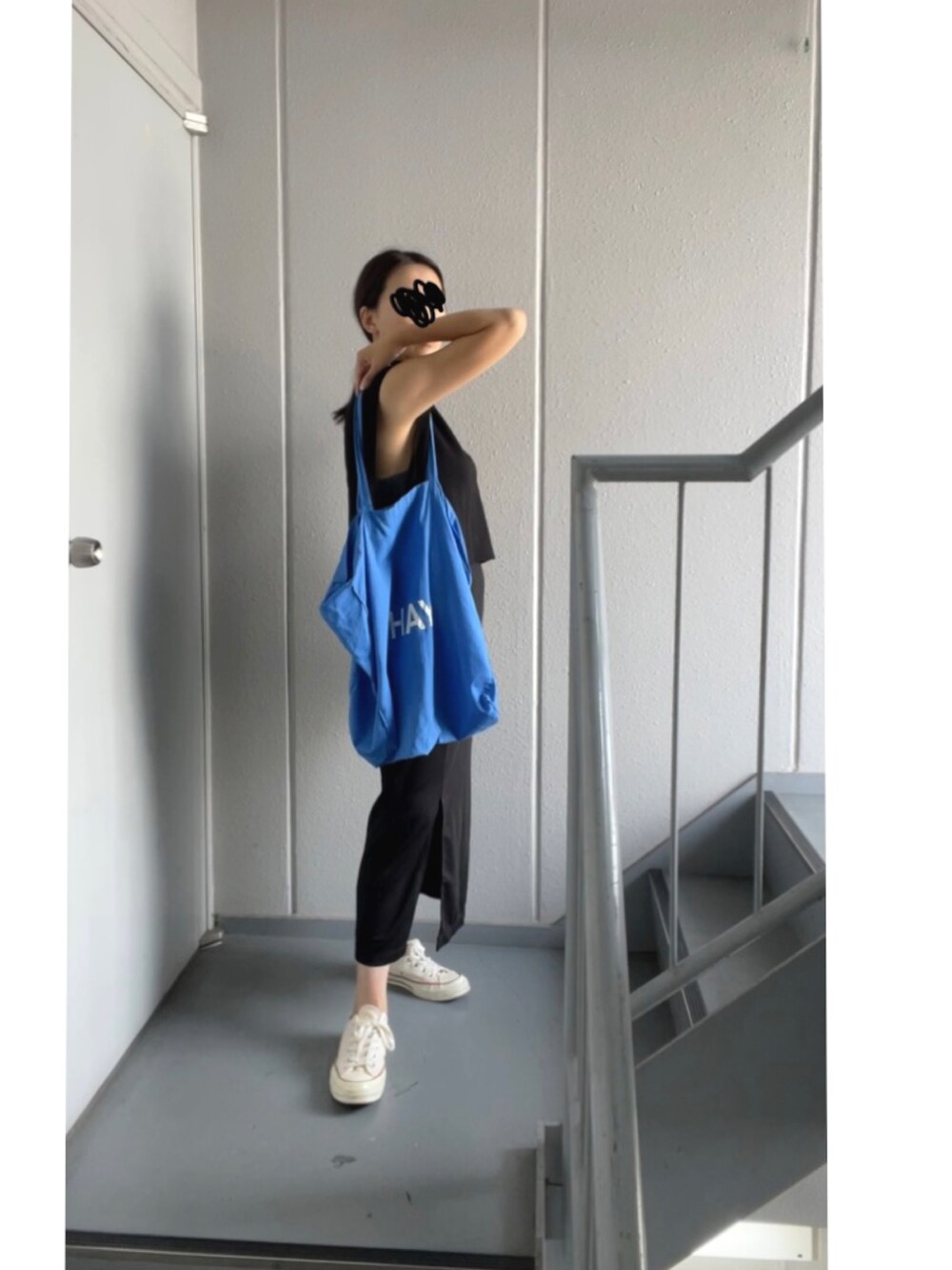 ブラック系のスカート、ホワイト系のスニーカー、ブルー系のトートバッグを着用したレディースの秋コーディネートの2枚目の写真