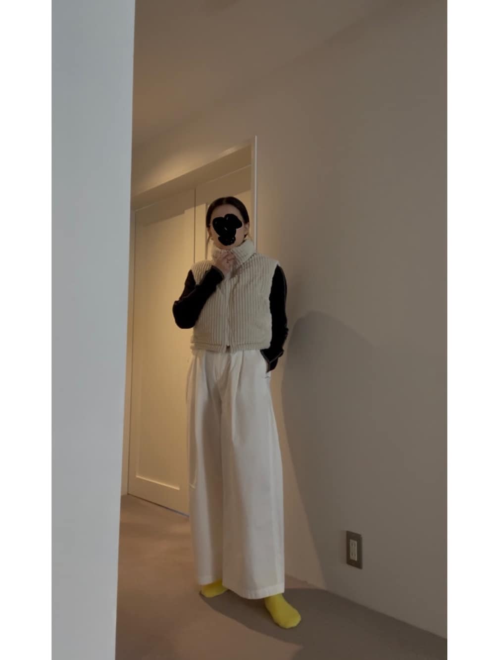 ホワイト系のベスト、ブラック系のニット/セーター、ブルー系のスニーカーを着用したレディースの春コーディネートの3枚目の写真