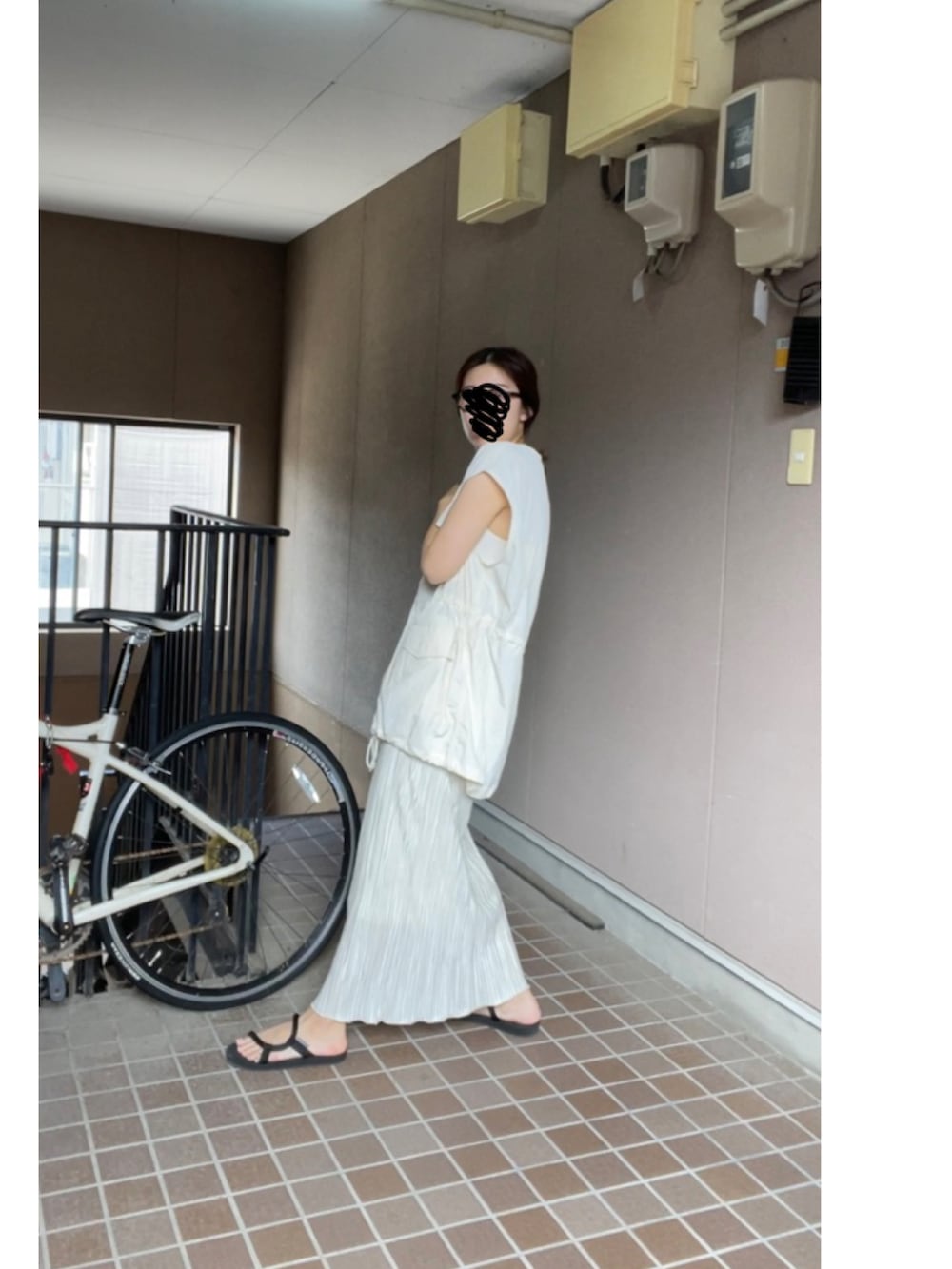 ホワイト系のベスト、ベージュ系のスカート、ブラック系のサンダルを着用したレディースの夏コーディネートの2枚目の写真