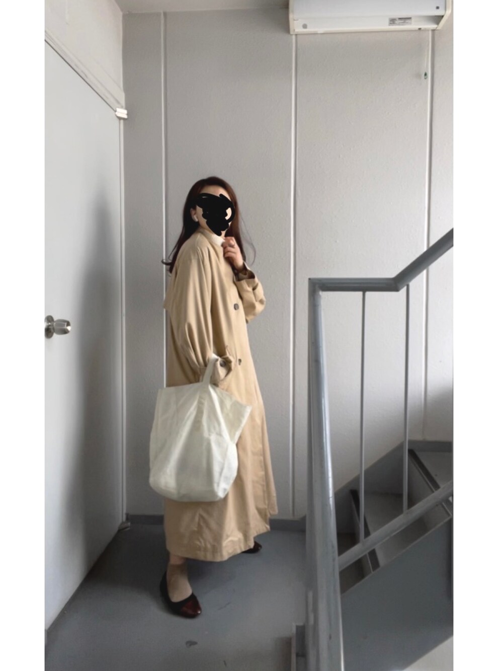 ホワイト系のトートバッグ、ホワイト系のニット/セーター、ベージュ系のトレンチコートを着用したレディースの冬コーディネートの2枚目の写真