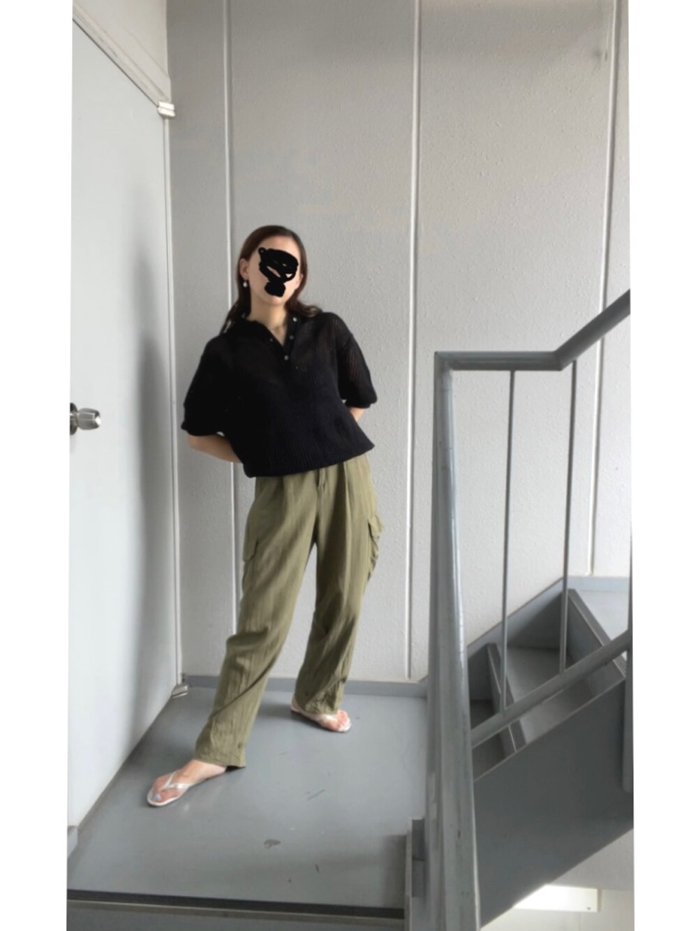 グリーン系のカーゴパンツ、ブラック系のポロシャツ、シルバー系のサンダルを着用したレディースの夏コーディネートの2枚目の写真