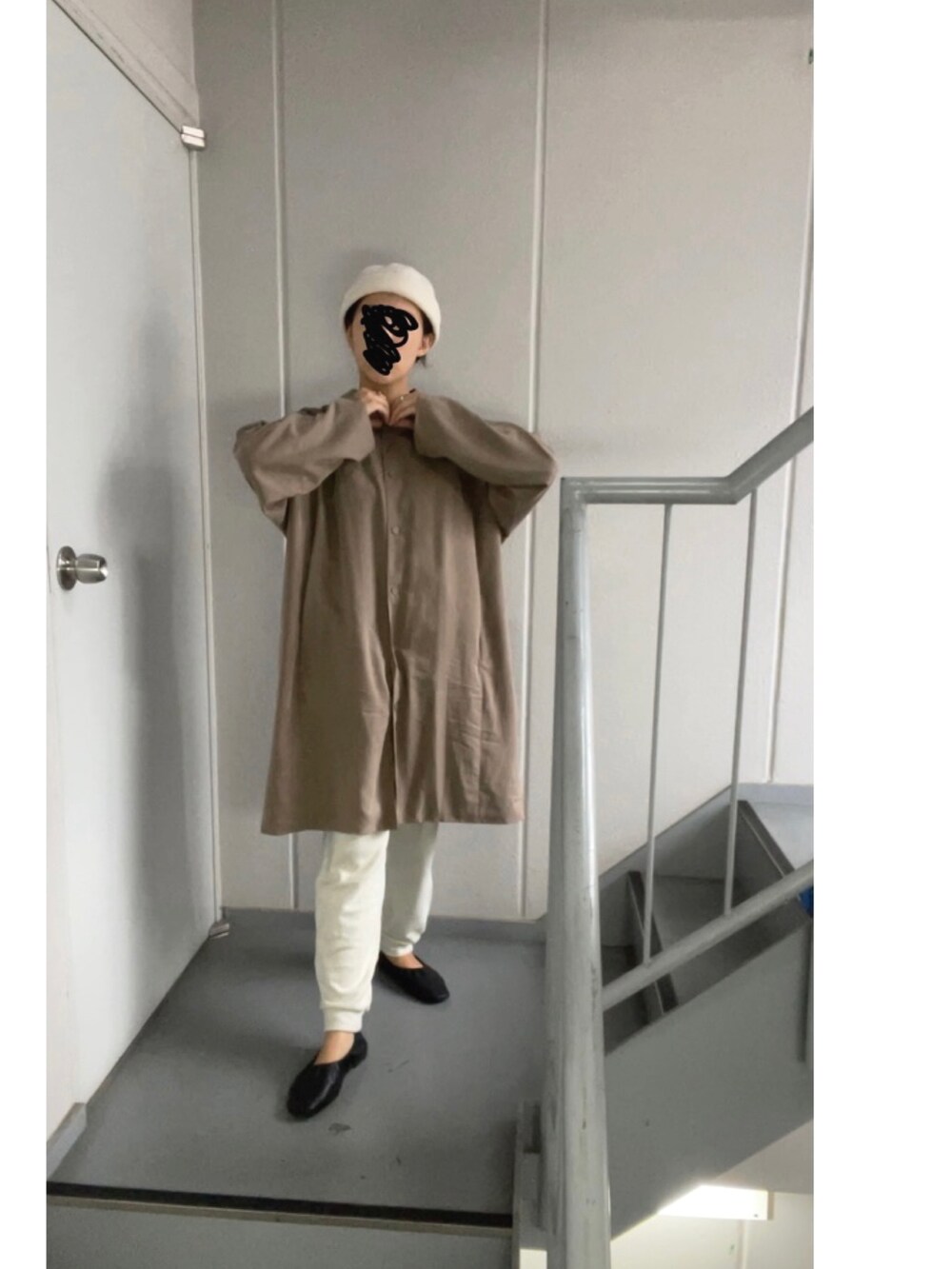 ブラウン系のステンカラーコート、ホワイト系のパンツ、ベージュ系のニットキャップ/ビーニーを着用したレディースの秋コーディネートの2枚目の写真
