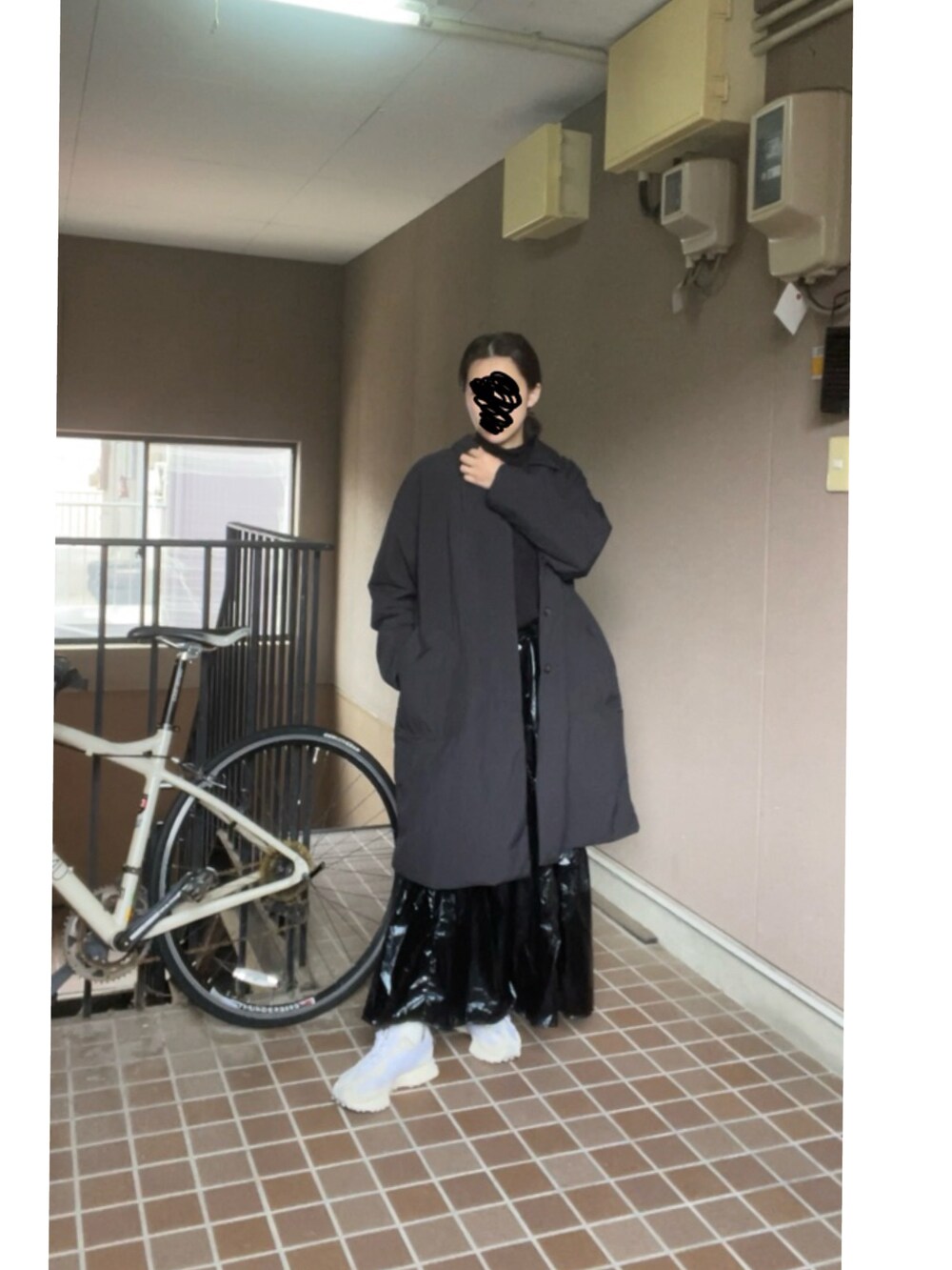 ブラック系のスカート、ホワイト系のスニーカー、ブラック系のその他アウターを着用したレディースの冬コーディネートの2枚目の写真