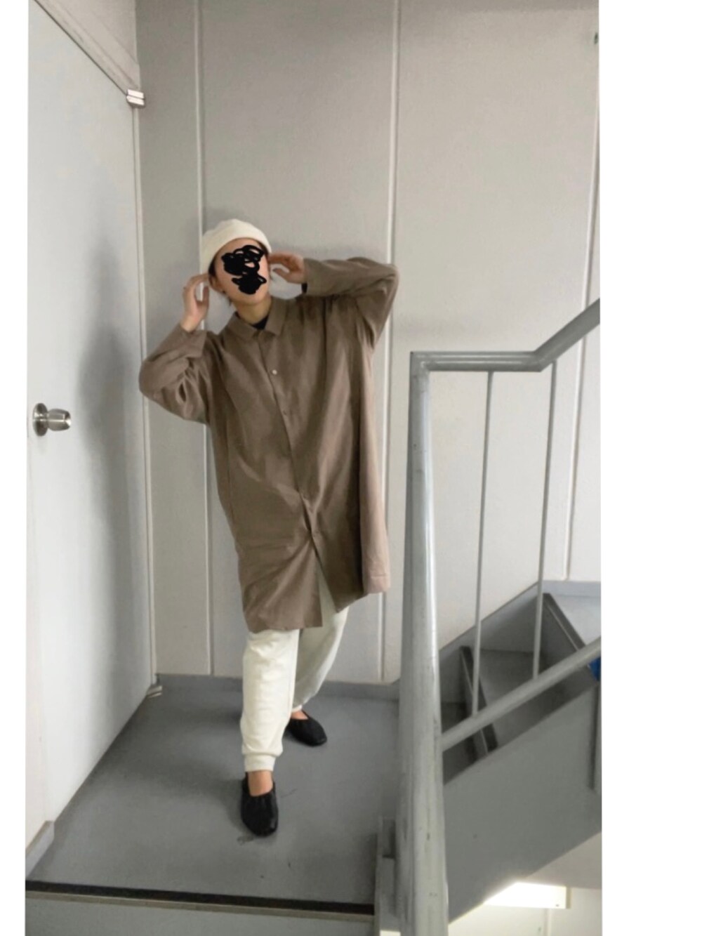 ブラウン系のステンカラーコート、ホワイト系のパンツ、ベージュ系のニットキャップ/ビーニーを着用したレディースの秋コーディネートの2枚目の写真