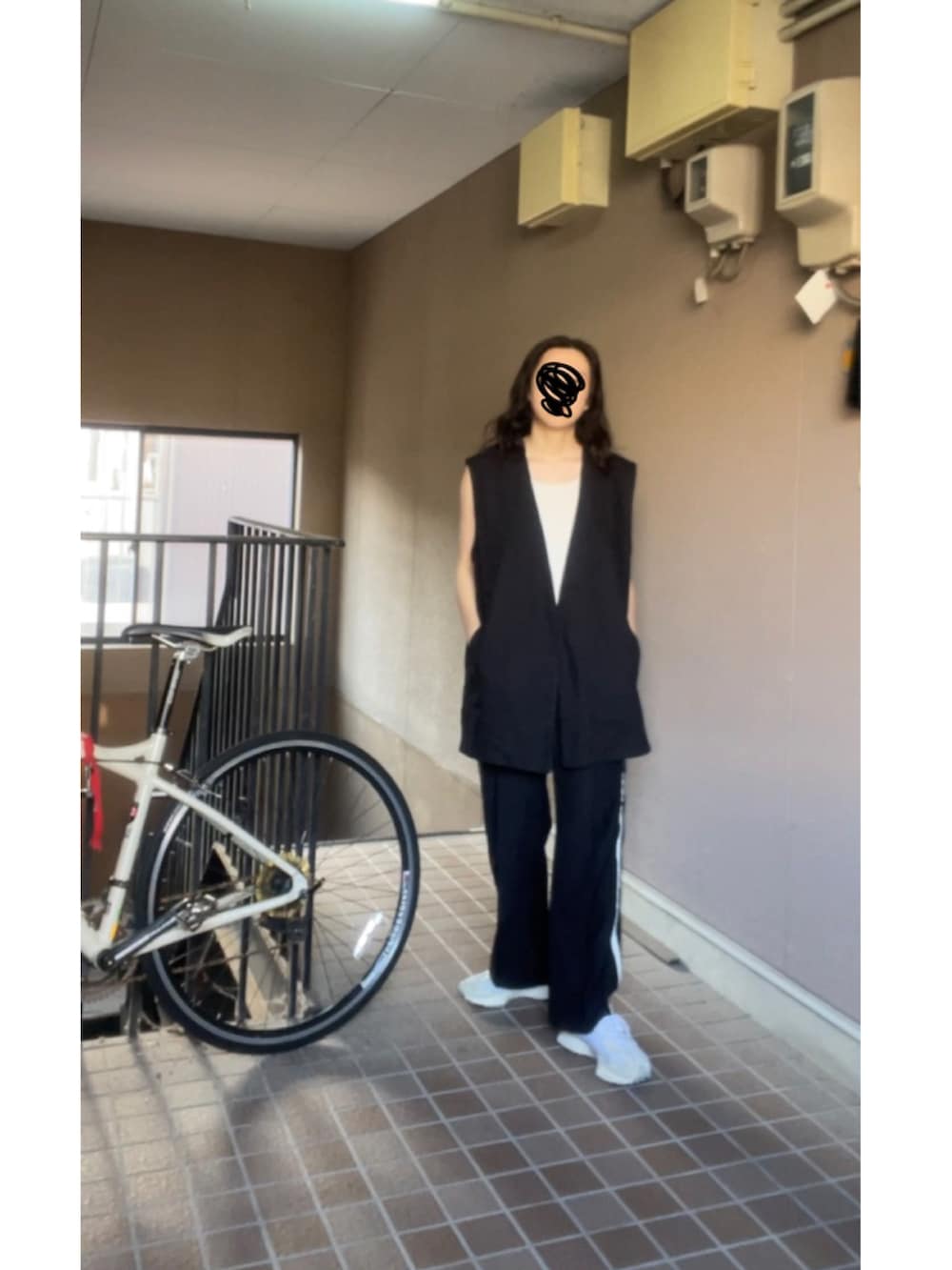 ブラック系のベスト、ブラック系のその他パンツ、ホワイト系のスニーカーを着用したレディースの春コーディネートの2枚目の写真