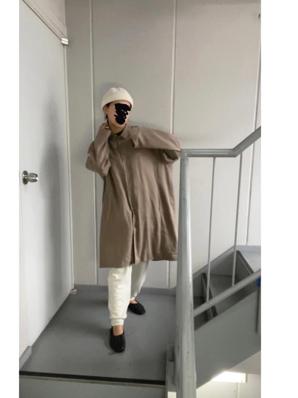 ブラウン系のステンカラーコート、ホワイト系のパンツ、ベージュ系のニットキャップ/ビーニーを着用したレディースの秋コーディネートの5枚目の写真